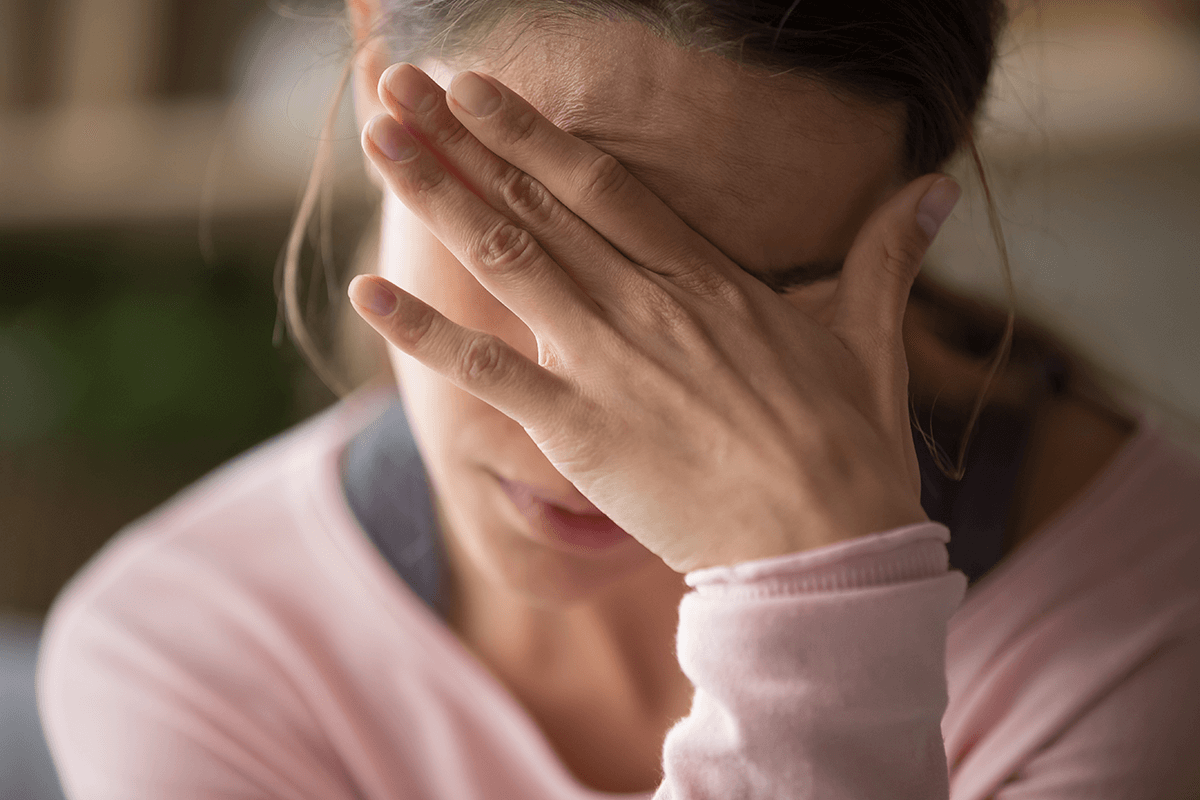 Sad tired young woman touching forehead